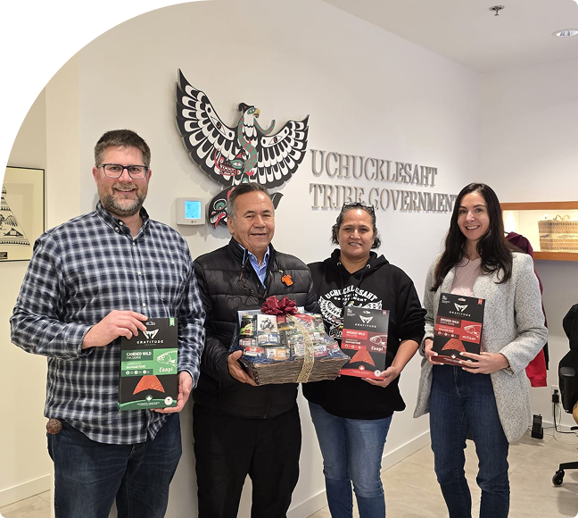 Four UTG staff members holding Gratitude gift boxes in front of the Uchucklesaht Tribe Government sign